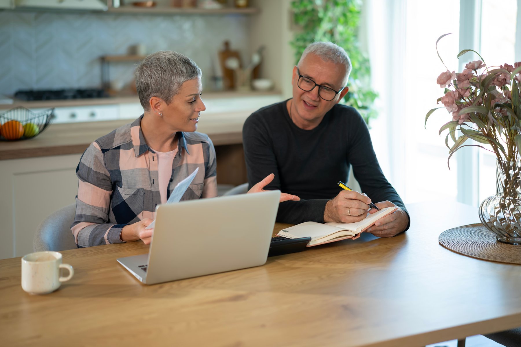 Couple reviewing insurance paperwork and a laptop at a kitchen table