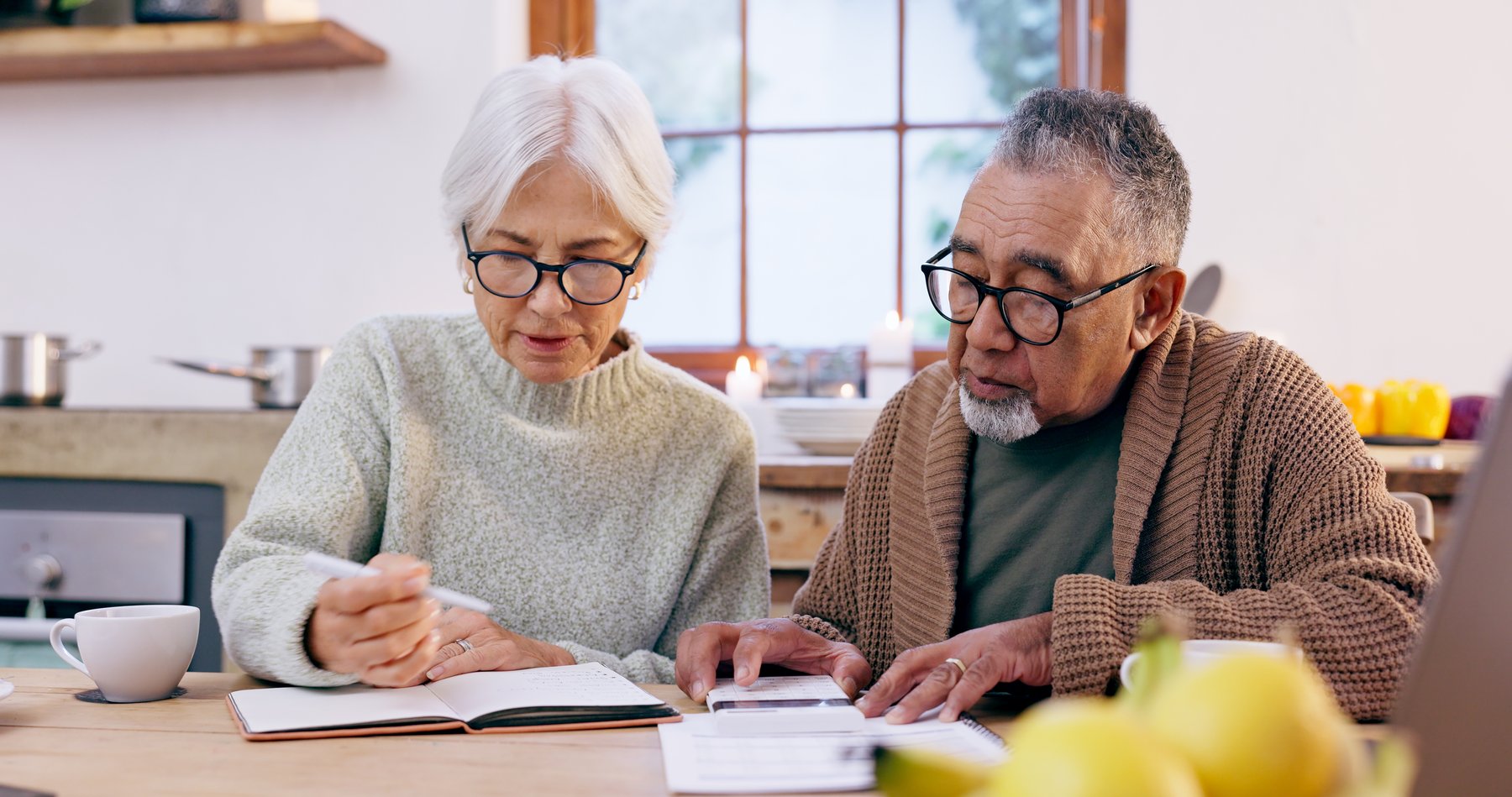 Senior couple at a kitchen table reviewing Medicare paperwork together